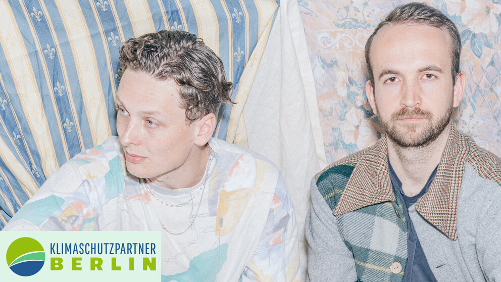 Zwei Männer sitzen vor Textilien