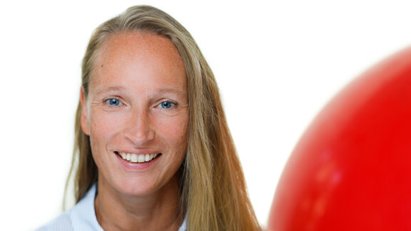 Porträtfoto von Kathrin Ohlmer, einer weißen Frau mit langen blonden Haaren, die in die Kamera lächelt