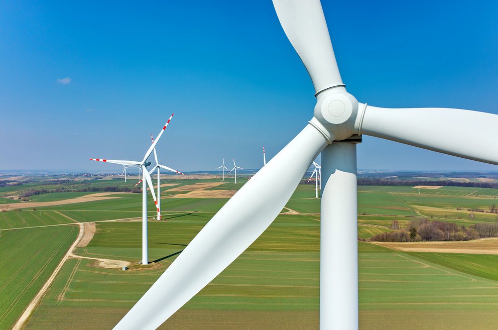 Zwei  Windräder stehen hintereinander in einem Feld