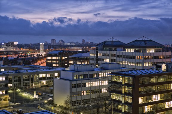 Blick auf beleuchtete Bürogebäude bei Abenddämmerung unter bewölktem Himmel
