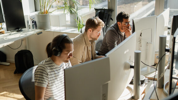 Drei Männer arbeiten am Computer. 