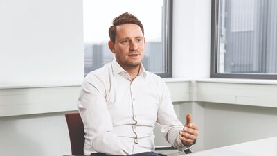 Zu sehen ist ein mittelalter Mann in weißem Hemd. Es handelt sich um Raphael Kube, Abteilungsleiter der IBB.