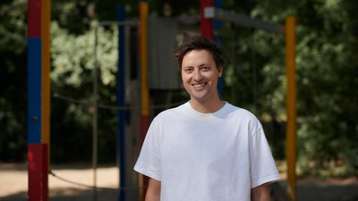 Ein Mann in einem weißen T-Shirt steht vor einem Klettergerüst.