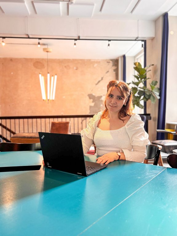 Vivian Alla sitzt am Tisch mit Laptop 