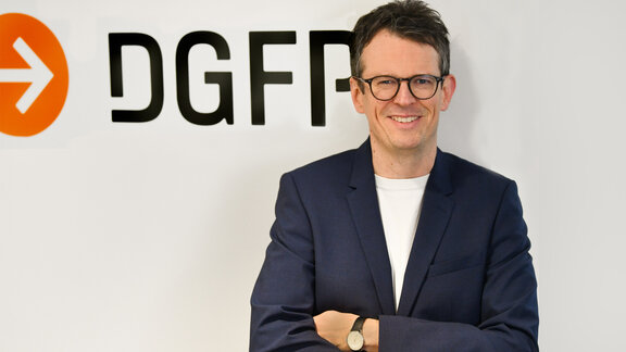 Christian Lorenz vor weißer Wand mit DGFP-Schriftzug.