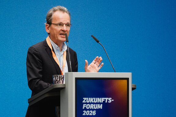 Zu sehen ist ein Mann hinter einem Redepult.