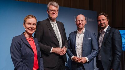 Zu sehen sind vier Personen, die freundlich in die Kamera lächeln. Es sind von links nach rechts: Hauptgeschäftsführerin der IHK Berlin Manja Schreiner, Bundesverkehrsminister Patrick Schnieder, Präsident der IHK Berlin Sebastian Stietzel und Vizepräsident der IHK Berlin Robert Rückel.