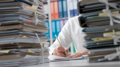 Symbolbild Bürokratie mit Aktenstapeln