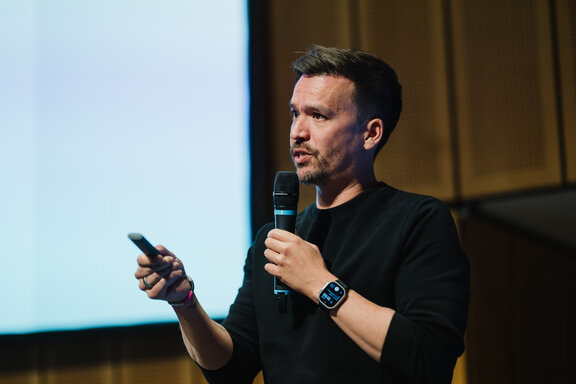 Vortragsszene beim Jakobb‑Kongress mit Präsentationsfolie im Hintergrund