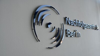 Zu sehen ist das Logo der Nachfolgezentrale Berlin an einer Wand.