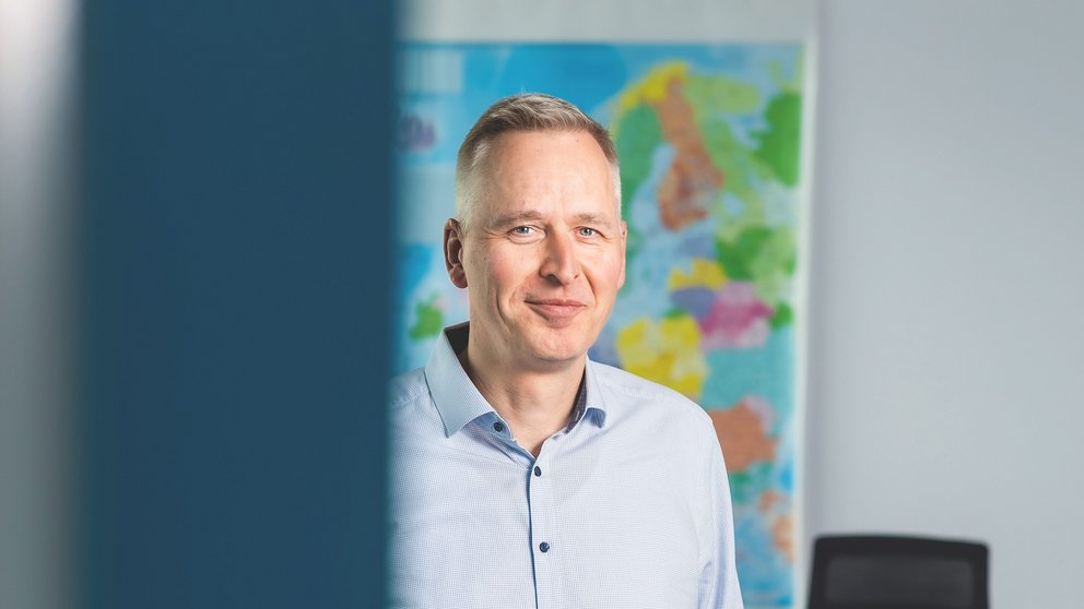 Auf dem Bild ist ein weißer Mann mit blauem Hemd und Jeanshose zu sehen.