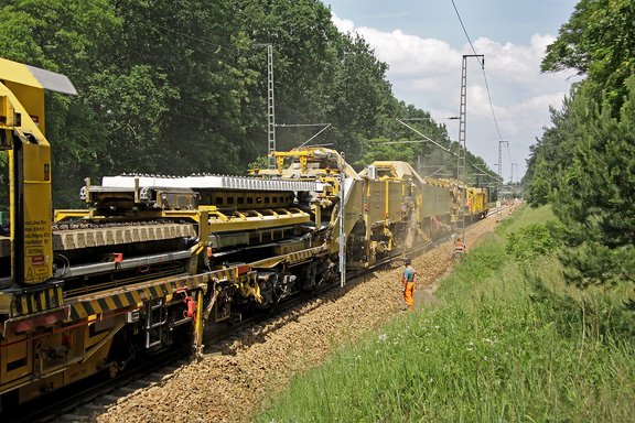 Baustelle mit Gleisbaumaschinen der GIGA GmbH auf einem Bahngleis, Arbeiter in Warnkleidung neben den Maschinen im Grünen