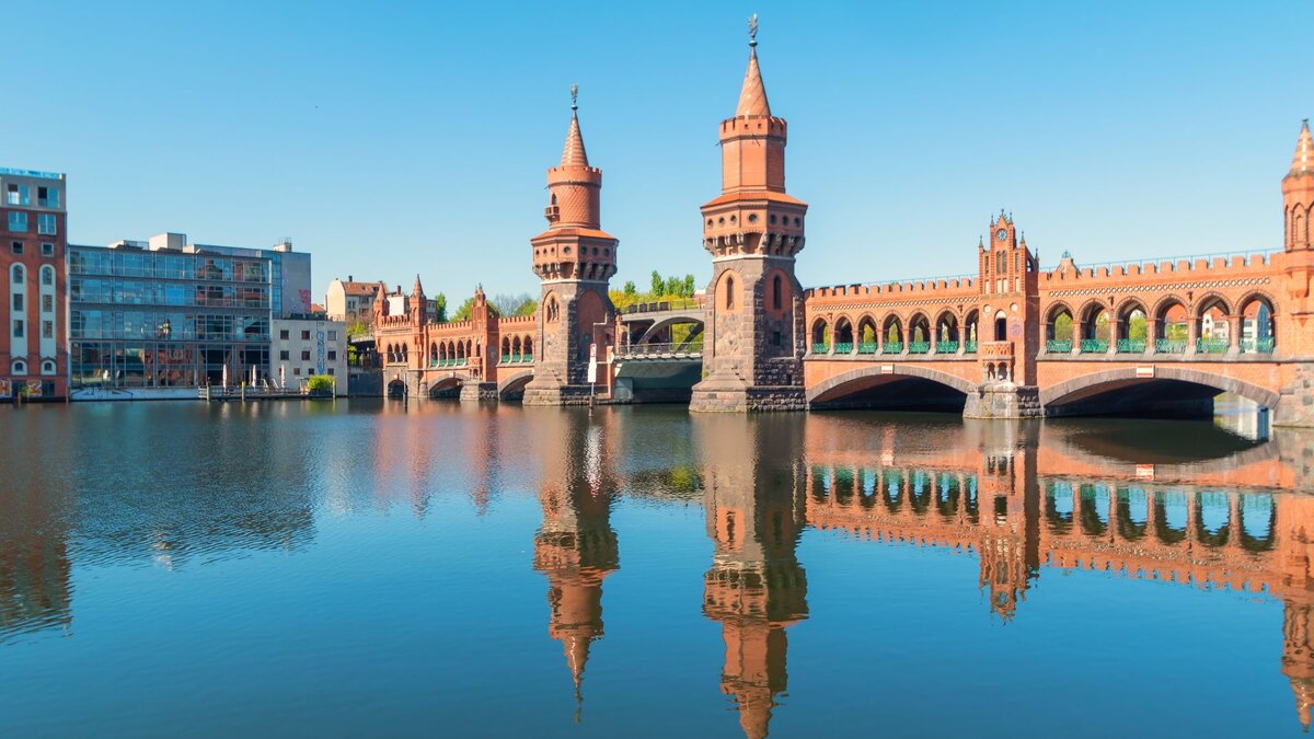 Zu sehen ist eine Brücke auf rotem Backstein, unter ihr fließt ein Fluss. Es handelt sich um die Oberbaumbrücke in Berlin, welche über die Spree führt.