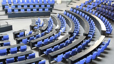 Zu sehen ist die blaue Bestuhlung eines großen Sitzungsraums. Es handelt sich um den deutschen Bundestag.