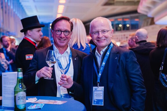 Zwei lächelnde Unternehmer mit Weinglas.