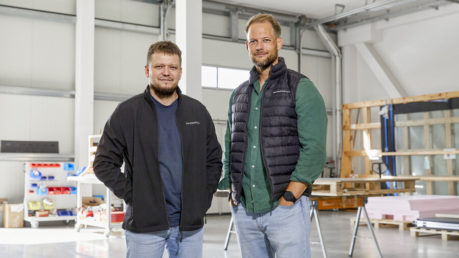 Nikita Fahrenholz und Philipp Engelmann stehen in einer hellen Werkstatt. 