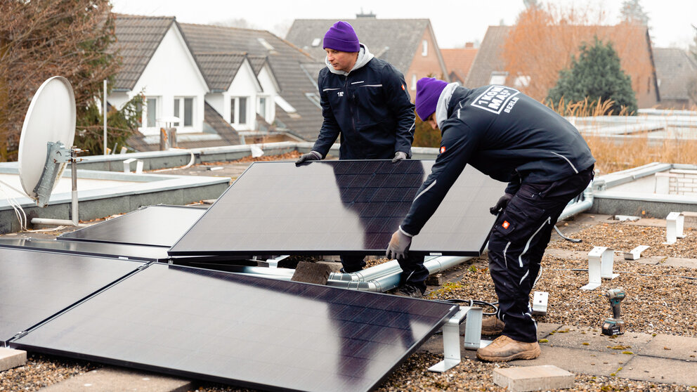 Zwei Männer montieren eine Solaranlage auf einem Flachdach – es symbolisiert das Thema Mitarbeitergewinnung.