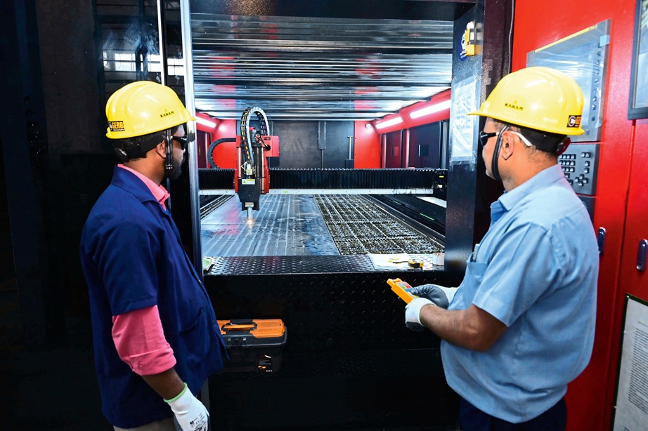 Zwei Männer in gelben Bauhelmen arbeiten an einer Schweißmaschine